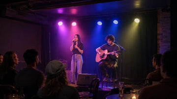 Small bar stage with singers lit by colorful LED PAR lights