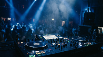 DJ controller at nightclub with stage lighting and crowd