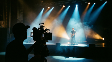 Concert stage filming with colorful DJ lighting and fog