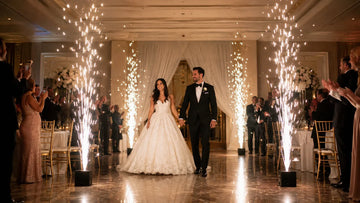 Bride and groom walking through indoor cold spark fountains at a wedding reception