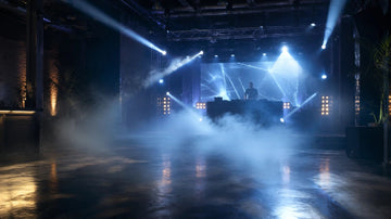 DJ performing on a fog-filled stage with blue spotlights