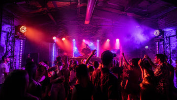 Crowded dance floor under red and purple DJ lights